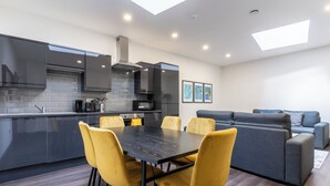 A modern kitchen with a dining area, built-in appliances, and a gray sofa in a living space. - Temple Court by UStay Aparthotels (Liverpool)