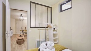 Habitación de hotel con cama, ventana, toallero y una pequeña mesa con una silla.