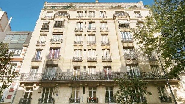 Un edificio de varios pisos con balcones y ventanas amplias.