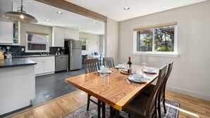 A modern kitchen with white cabinets, a wooden dining table, and a large window. - Magnolia Hideaway - Pet Friendly w/ Fireplace (Fort Collins)