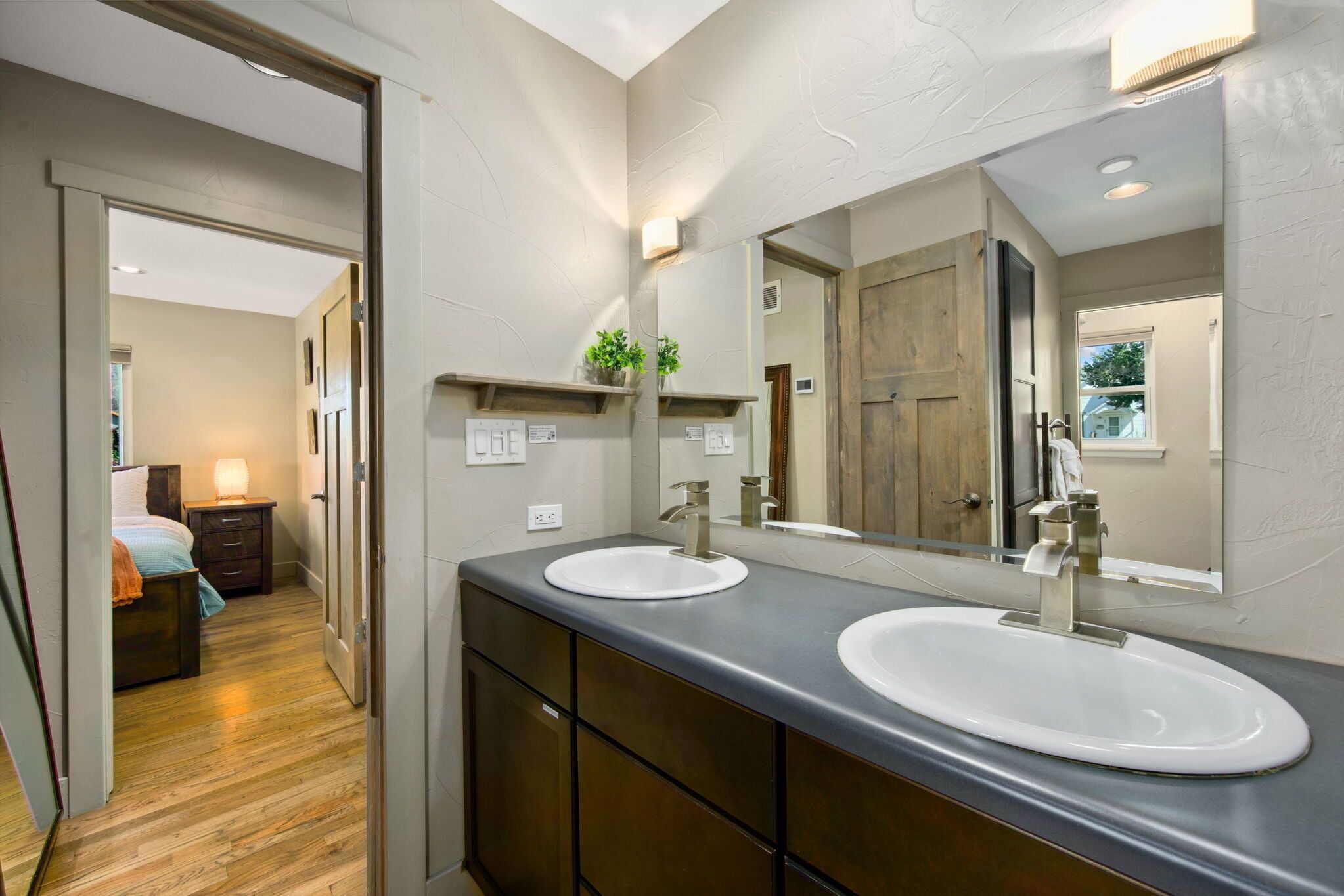 A bathroom with two sinks, a large mirror, and a wooden door.