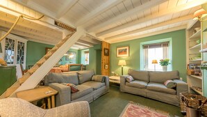A cozy living room with two sofas, a small table, and a staircase.