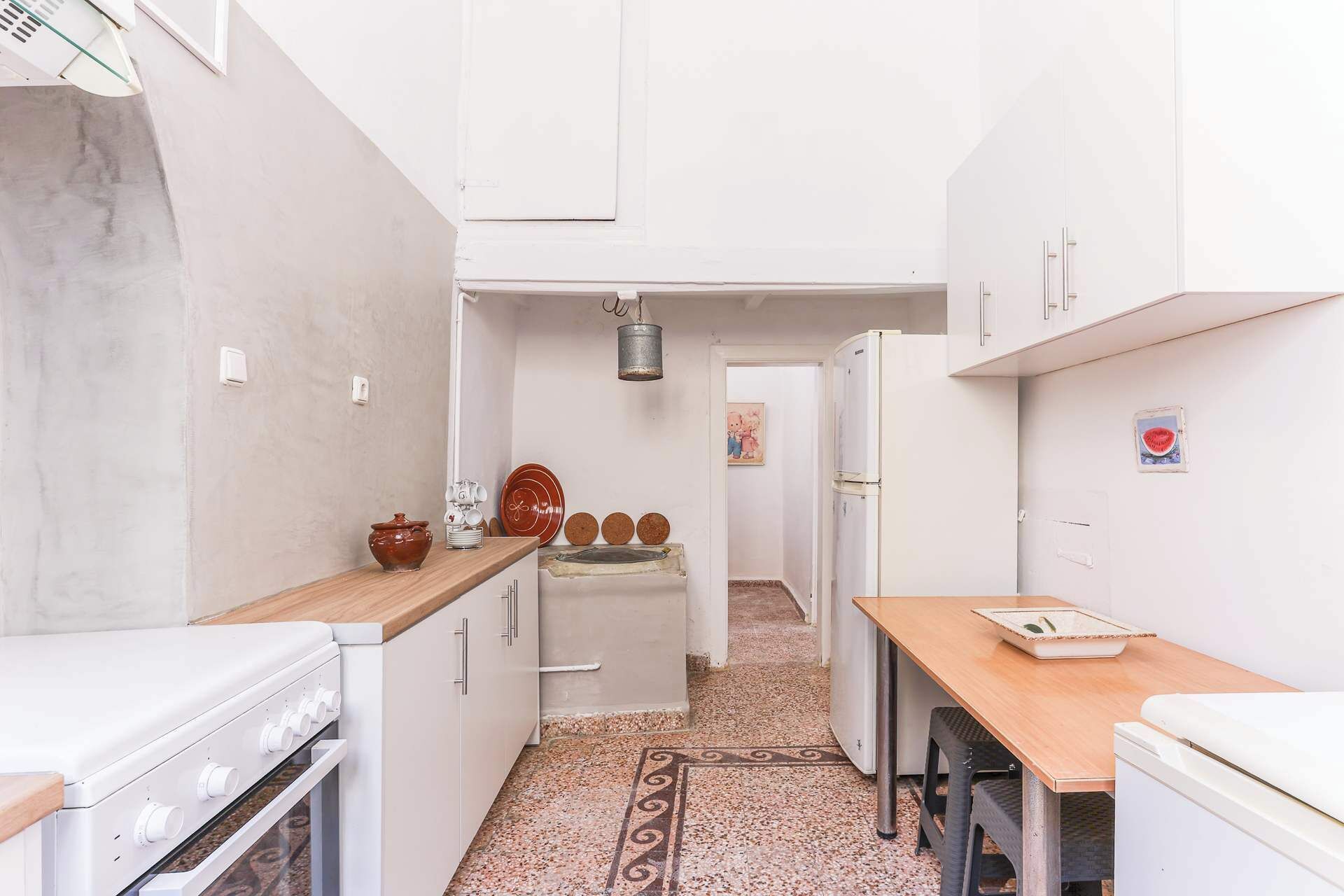 Una cocina estrecha con armarios blancos, encimera de madera, estufa y refrigerador.