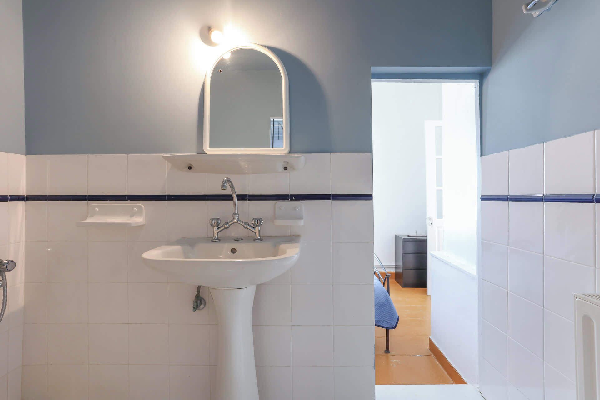 A bathroom with a white sink, a mirror, and a shower.