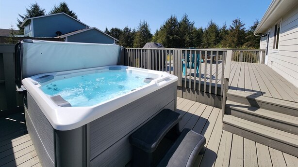 Een jacuzzi op een houten terras, met uitzicht op een huis en bomen.
