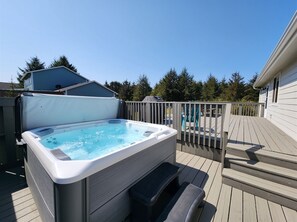 A hot tub on a wooden deck with a view of a house and trees in the background.