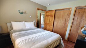 Een slaapkamer met een bed, een houten garderobe en een decoratieve zeemeermin aan de muur.