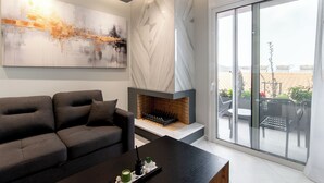 Ein modernes Wohnzimmer mit Kamin, einem großen abstrakten Gemälde und Blick ins Freie.