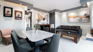 Ein modernes Wohnzimmer mit Essbereich, grauen Sofas, einem Couchtisch und einem großen abstrakten Gemälde an der Wand.