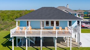 Ein zweistöckiges Haus mit Balkon, mehreren Fenstern und einer Terrassenfläche mit Sitzgelegenheiten.