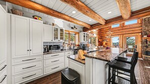 A spacious kitchen with white cabinetry, a large island, and wooden beams on the ceiling. - The Broadmeadow Cabin - Vr-25-0005 3 Bedroom Cabin (Lyons)