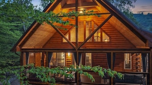 Eine Holzhütte mit Glasbalkon, umgeben von Bäumen.