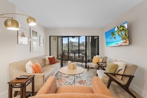 A living room with a sofa, armchairs, a coffee table, and a TV mounted on the wall. - Unique Two-Story Cabana Condo| Anglers Cove (Marco Island)