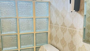 Une salle de bain comprenant des toilettes, un lavabo et un espace douche séparé par une paroi en verre.