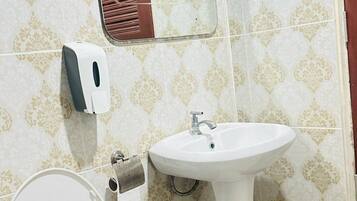 Un baño con inodoro, lavamanos y espejo.