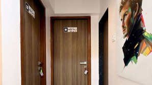 A hallway with wooden doors, a marble floor, and a pair of sandals on the floor. - 2BHK Master Suite (Gagal Home) (Mumbai)