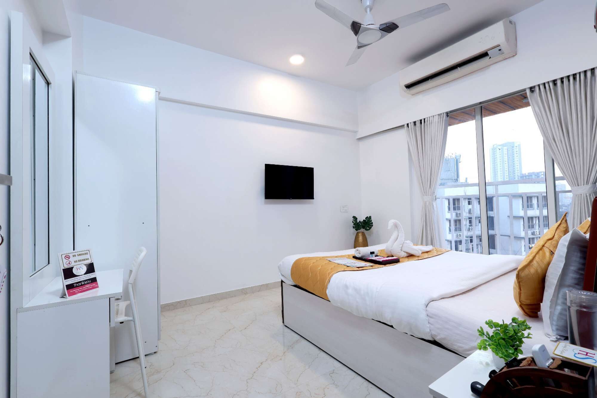Une chambre d’hôtel avec un lit, un bureau, une télévision et une fenêtre donnant sur la ville.