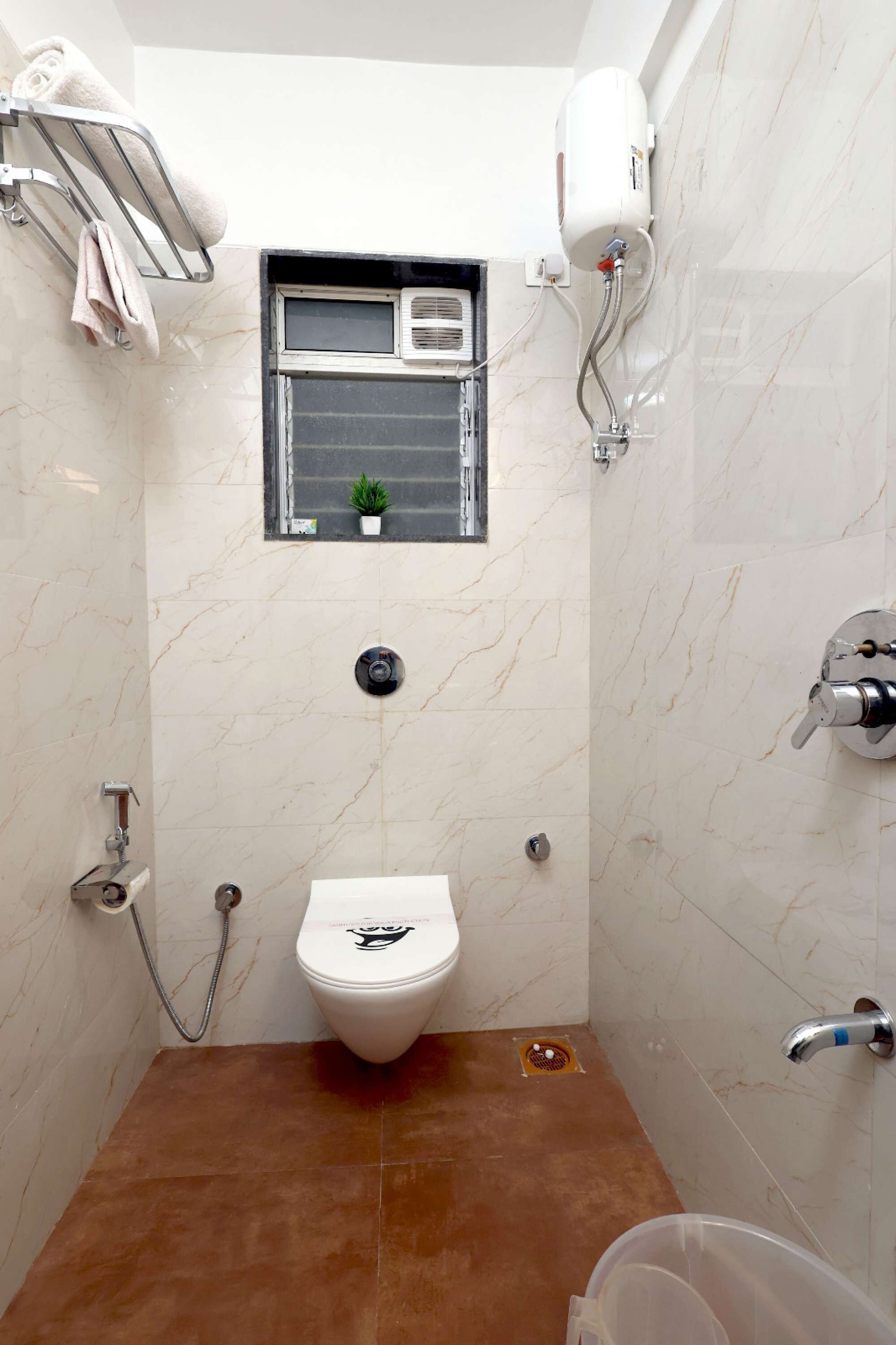 A compact bathroom with a toilet, a shower, and a small window.