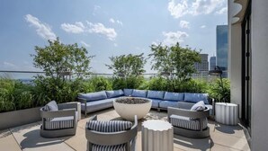A rooftop patio with a sectional sofa, a round coffee table, and a seating area with striped cushions.
