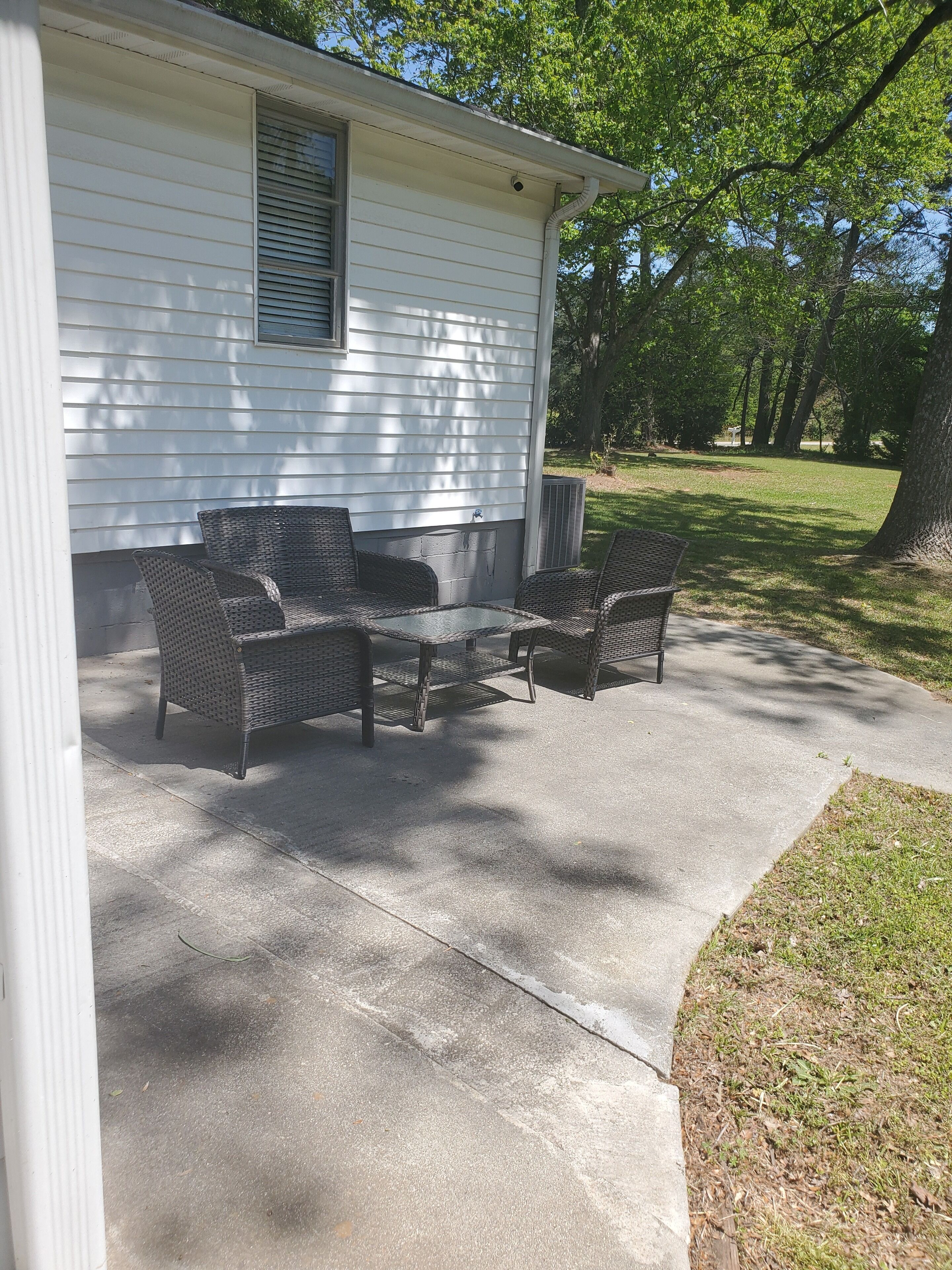 A covered patio with wicker furniture and a concrete floor.