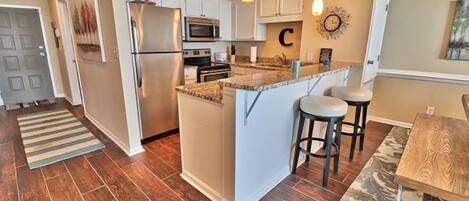 A kitchen with a central island, white cabinetry, a refrigerator, and a microwave.