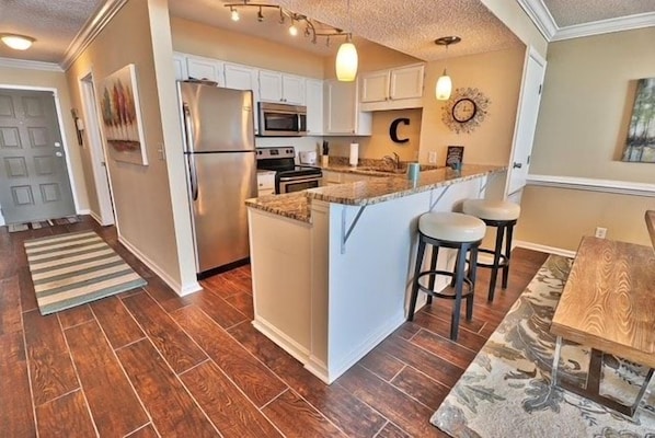 A kitchen with a central island, white cabinetry, a refrigerator, and a microwave.