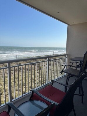 A balcony with a view of the beach, a table, and chairs. - Oceanfront 3BR Family Condo with Pool and Views (North Myrtle Beach)