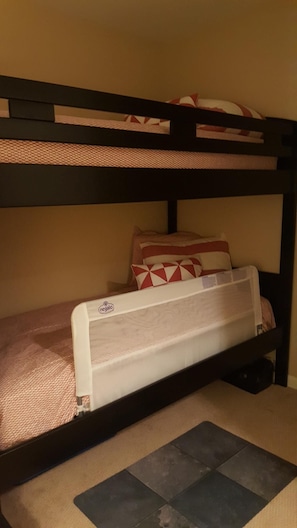 A bunk bed with a mattress and pillows, a small heater, and a carpeted floor.
