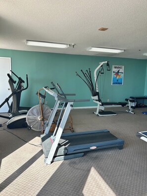 A gym with exercise equipment including treadmills, a stationary bike, and a fan.