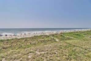 A beach with a grassy area in the foreground and a clear sky.