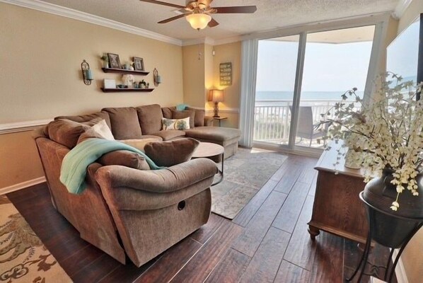 A living room with a sofa, a coffee table, and a view of the ocean.