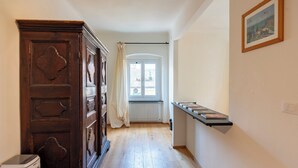 A hallway with a wooden door, a radiator, a window with curtains, and a shelf with books. - Lovely House in Boccadasse (Genoa)