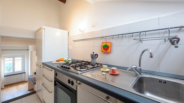 A modern kitchen with a gas stove, sink, and white cabinets. - Lovely House in Boccadasse (Genoa)