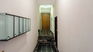 A narrow hallway with a wooden door at the end, a metal railing on the left, and a tiled floor with a diamond pattern. - Lovely House in Boccadasse (Genoa)