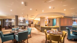 A hotel lobby with round tables, chairs, a reception desk, and a bar area. - Premier Inn Liverpool City Centre - Moorfields (Liverpool)