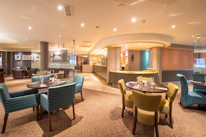 A hotel lobby with round tables, chairs, a reception desk, and a bar area. - Premier Inn Liverpool City Centre - Moorfields (Liverpool)