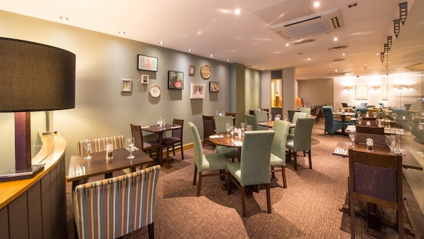 A hotel dining area with multiple tables, chairs, and a bar counter. - Premier Inn Liverpool City Centre - Moorfields (Liverpool)