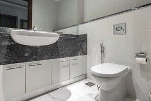 Une salle de bain moderne avec un lavabo blanc, un plan de toilette en marbre et des toilettes.