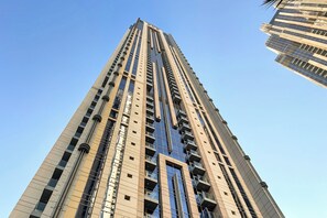 Un immeuble moderne et imposant, doté d’une façade centrale en verre et de nombreux balcons.