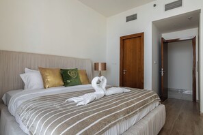 Une chambre d’hôtel avec un lit bien fait, une porte en bois et une salle de bain visible à travers une porte entrouverte.