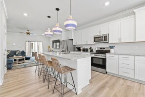A modern kitchen with white cabinets, stainless steel appliances, and a central island with bar stools.