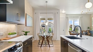 A modern kitchen with a central island, stainless steel appliances, and a view to the outside. - The Highland Retreat | Gym, Sauna, Pool & Spa (Windsor)