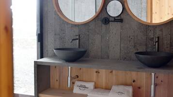 A bathroom with two round mirrors, a wooden vanity, and a sink with a bowl design.