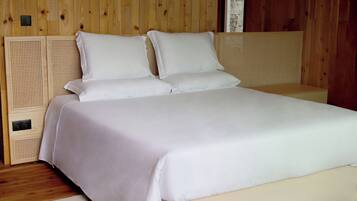 A bed with white linens in a room with wooden panel walls and a wooden headboard.