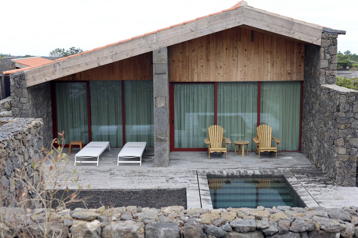 A modern building with a stone facade, large sliding glass doors, and a pool area with lounge chairs.