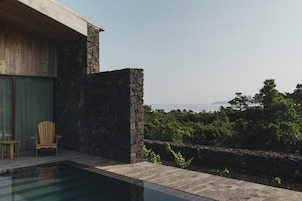 Un edificio moderno con fachada de piedra, una terraza de madera y una piscina.