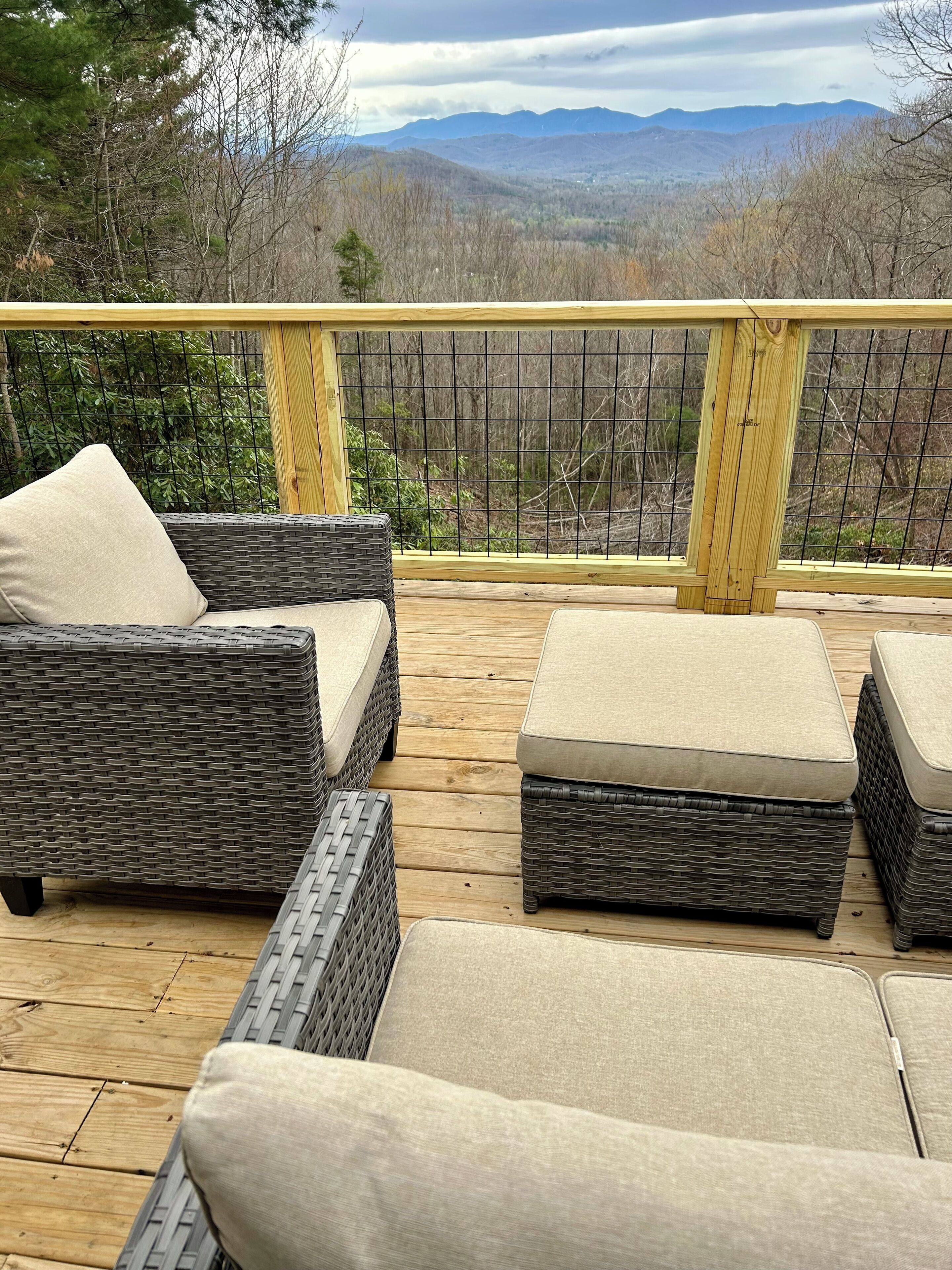 Une terrasse en bois, meublée de mobilier en osier, avec vue sur les montagnes.