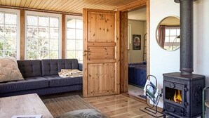 Ein gemütlicher Raum mit einer Couch, einer Holztür, einem Kamin und einem Fenster.