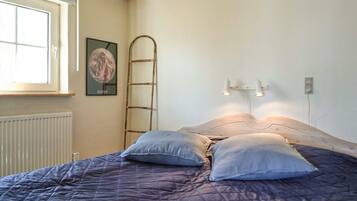 Un dormitorio con cama, escalera, cartel y ventana.