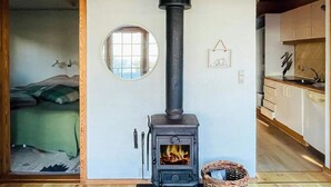 Ein gemütliches Zimmer mit Kaminofen, runder Spiegel und Korb.